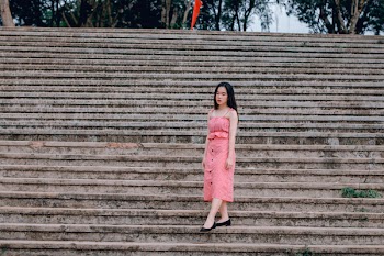 Woman Wearing Pink Spaghetti-strap Dress Standing on Grey Concrete Stairs