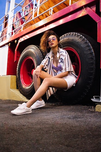 Woman Wearing Purple Bra and White Denim Short Sitting on Tire