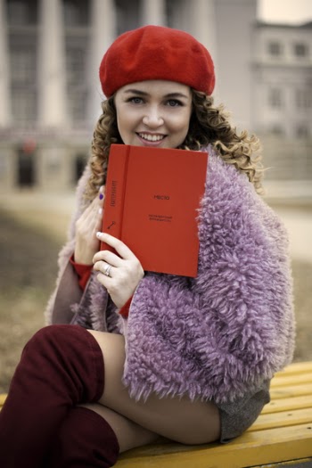 Woman Wearing Purple Coat and Gray Shorts Sitting on Brown Chair