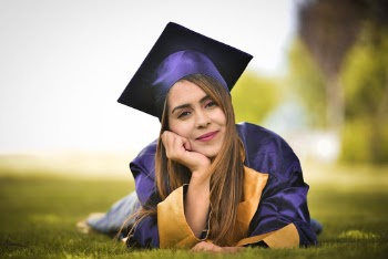 Woman Wearing Purple Graduation Gown Lying on Field