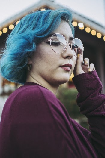 Woman Wearing Purple Long-sleeved Shirt While Holding Eyeglasses With Left Hand