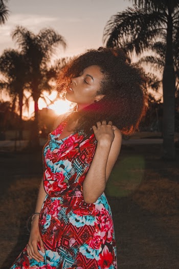 Woman Wearing Red and Blue Dress With Eyes Closed Standing Near Green Palm Trees