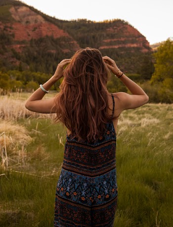 Woman Wearing Red and Blue Floral Dress Standing Beside Mountain