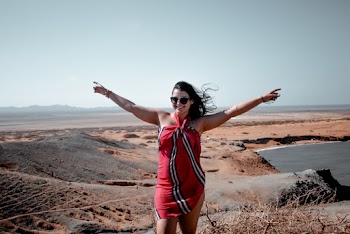 Woman Wearing Red and White Halter Dress Standing in the Middle of Dune Sand
