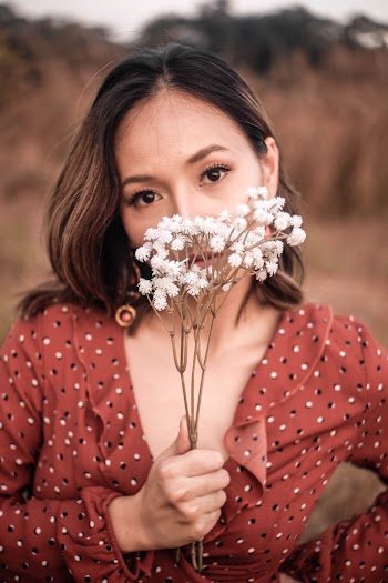 Woman Wearing Red, Black, and White Polka-dotted Long-sleeved Top Holding White Flowers
