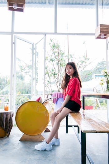 Woman Wearing Red Blouse and Black Short While Sitting on Table