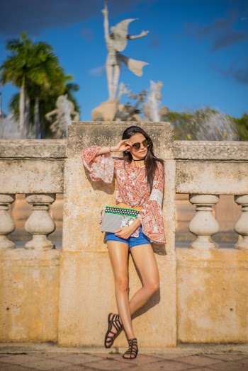 Woman Wearing Red Blouse And Blue Shorts Leaning On Wall