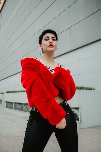 woman wearing red coat standing beside gray building