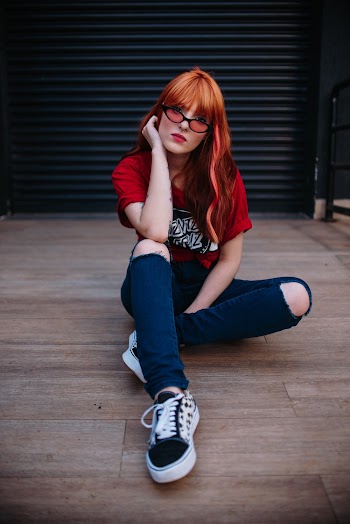 Woman Wearing Red Crew-neck Top Sitting on Brown Plankboard