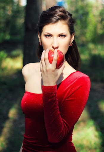 Woman Wearing Red Dress Holding Apple to her Mouth