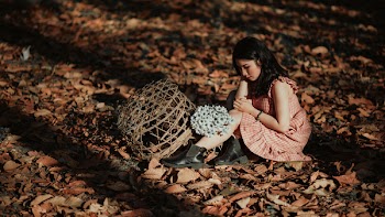 Woman Wearing Red Dress Sitting on Brown Ground With Woven Brown Basket