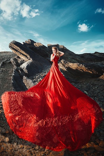Woman Wearing Red Dress Standing on a Rocky Hill