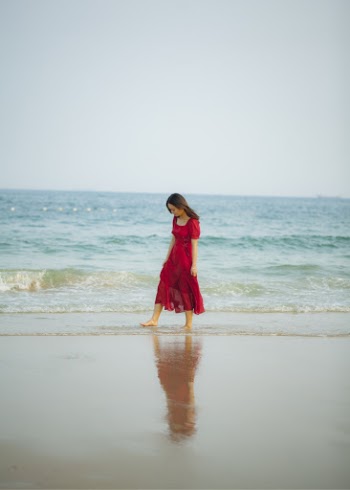 Woman Wearing Red Dress While Walking at Beach