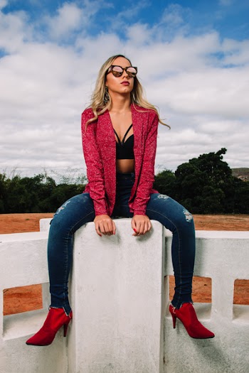 Woman Wearing Red Jacket and Distressed Blue Denim Skinny Jeans Sitting on Bench