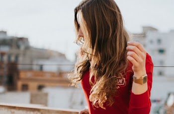 woman wearing red long-sleeved shirt standing near rail