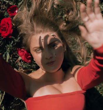 Woman Wearing Red Long-sleeved Top Lying on Red Roses