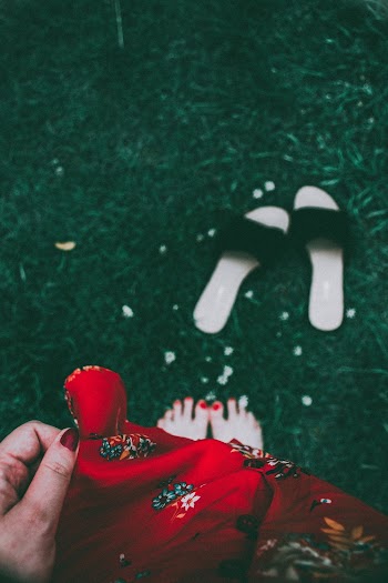 Woman Wearing Red Printed Dress Standing on Green Grass Barefooted