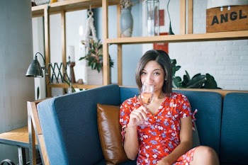 Woman Wearing Red, Purple, and Pink Floral V-neck Cap-sleeved Dress Drinking Through Clear Wine Glass