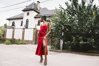 Woman Wearing Red Spaghetti Strap Split Dress in Front of White and Gray House