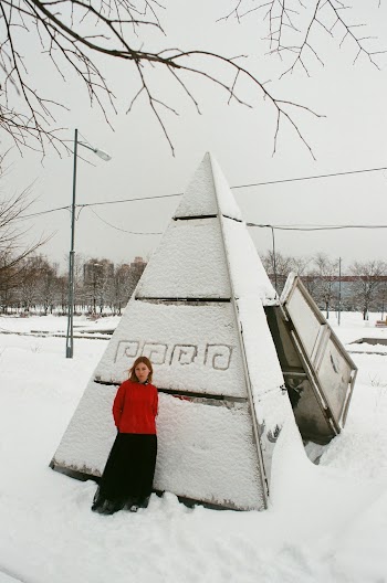 Woman Wearing Red Sweater and Black Skirt Standing on Triangular Hutch
