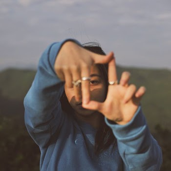 woman wearing rings and blue top taking selfie