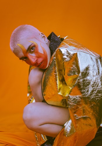 Woman Wearing Silver Zip-up Jacket Kneeling on Orange Textile