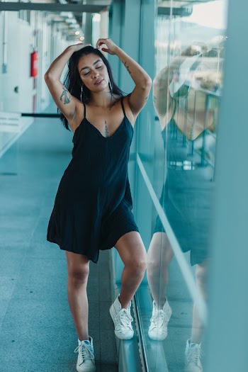 Woman Wearing Spaghetti Strap Dress Standing Next to Glass Wall