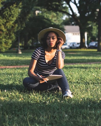 Woman Wearing Stripped Shirt Sitting in a Grass Field