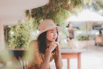 Woman Wearing Sun Hat Sitting Beside Table