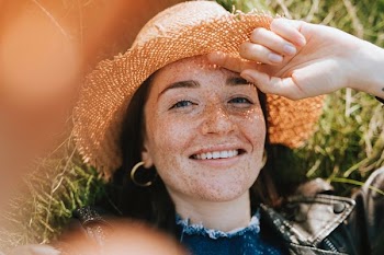 woman wearing sun hat while lying on grass