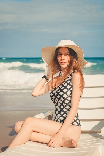 Woman Wearing Sun Hat While Sitting on Sun Lounger