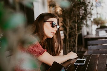 Woman Wearing Sunglasses Sitting Beside Table