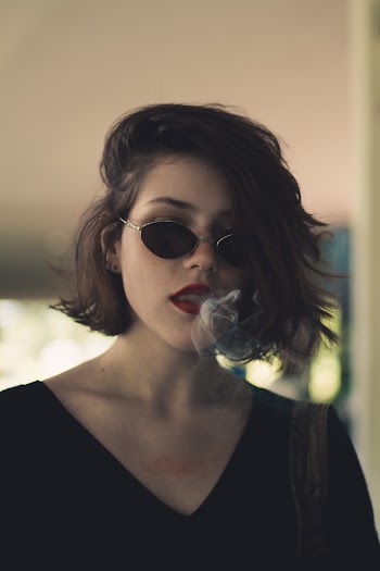Woman Wearing Sunglasses With Smoke in Mouth