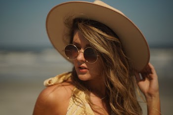 Woman Wearing Sunhat and Sunglasses by the Seashore