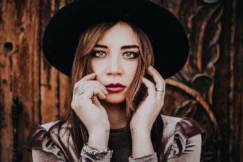 woman wearing sunhat posing near wall