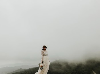 woman wearing wedding gown standing on top of hill