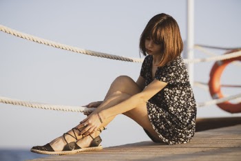Woman Wearing White and Black Floral Dress Sitting on  Wooden Boardwalk