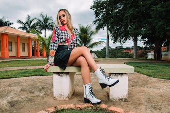 Woman Wearing White and Black Houndstooth Long-sleeved Top and Black Leather Skirt While Sitting on White Concrete Bench
