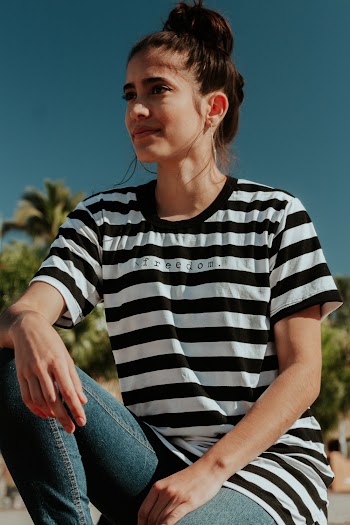 Woman Wearing White and Black Striped T-shirt and Blue Jeans Sitting Down