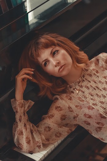 Woman Wearing White and Brown Floral Crew-neck Long-sleeved Shirt Lying on Black Piano