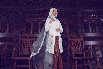 Woman Wearing White and Gold Traditional Dress Standing Beside Two Brown Wooden Armchairs