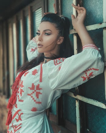 Woman Wearing White and Red Dress Standing and Leaning Against the Wall While Raising Both Hands