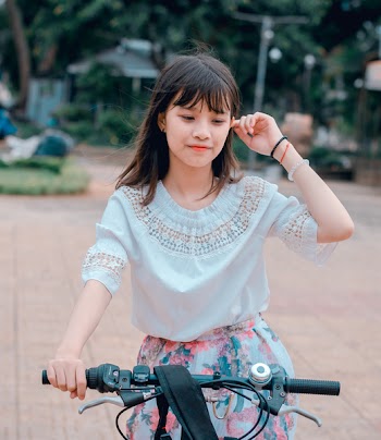 Woman Wearing White Blouse and Multicolored Floral Skirt Riding Bike