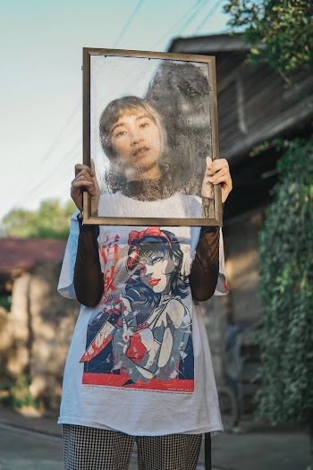 Woman Wearing White, Blue, and Red Woman Graphic Crew-neck T-shirt Standing While Holding Photo Frame