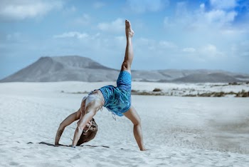 Woman Wearing White Bra and Blue Shorts Doing Yoga on Sand
