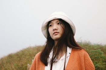 woman wearing white bucket hat and orange cardigan