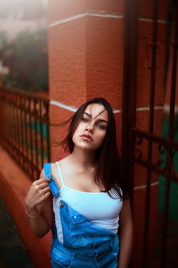 Woman Wearing White Camisole And Blue Dungaree Standing Beside Gate