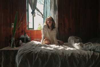 Woman Wearing White Crew-neck Sweater Sitting on Bed Near Open Window