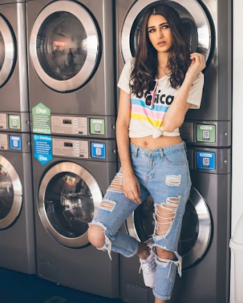 Woman Wearing White Crop-top and Distressed Blue Denim Jeans Leaning on Laundry Machine