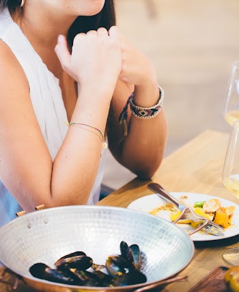 Woman Wearing White Deep V-neck Sleeveless Top Sitting on Chair Near Table